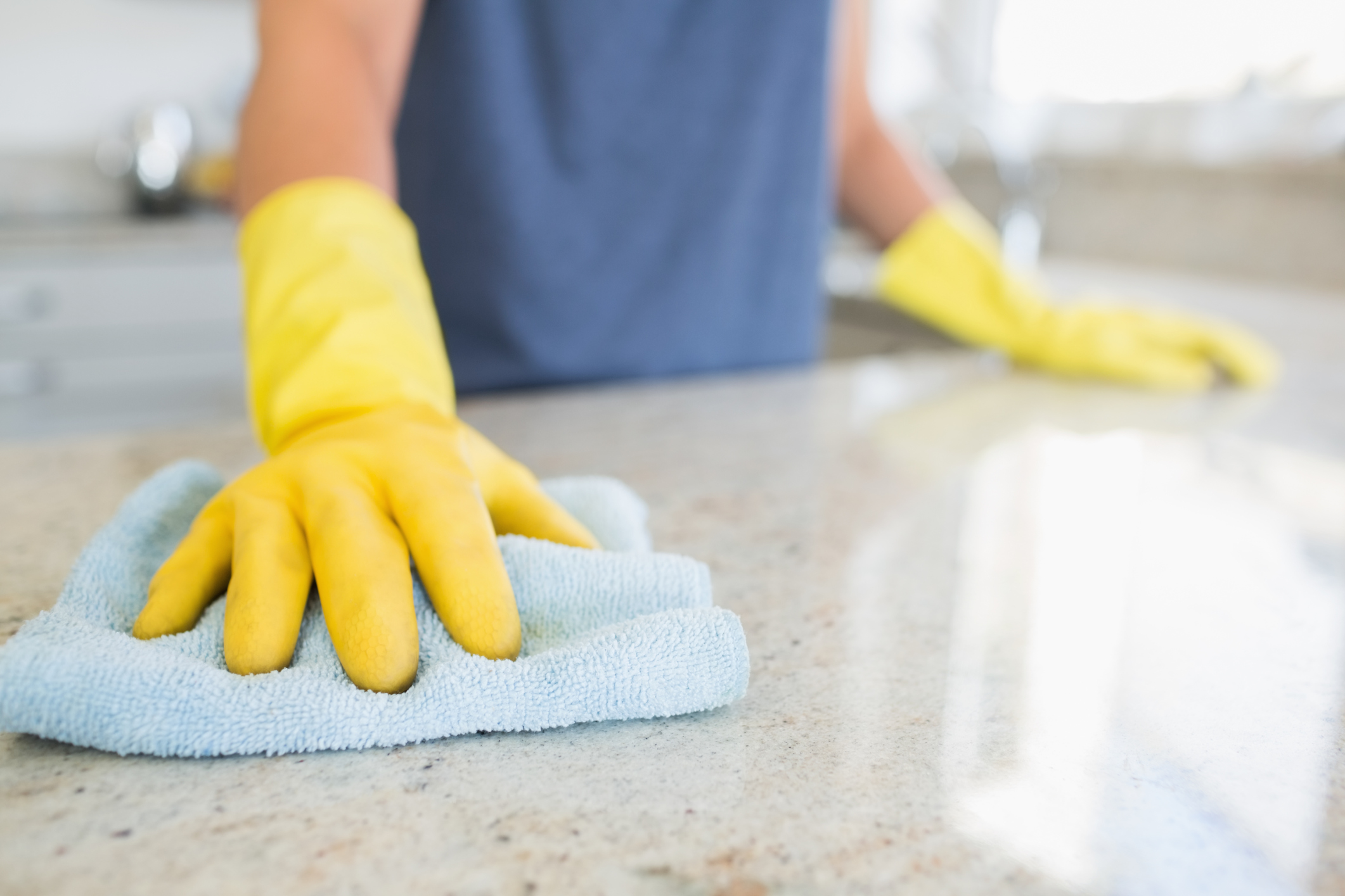 woman-cleaning-counter-with-rubber-gloves-on